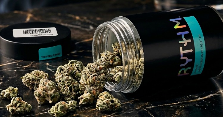 A glass jar of RYTHM Afternoon Delight #4 tipped over on a black marble surface with dense, frosty cannabis buds spilling out.