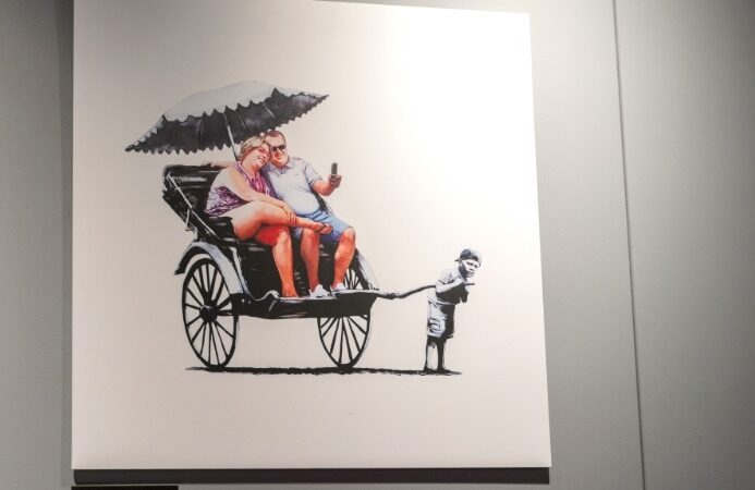 Banksy-style artwork of a couple riding in a rickshaw pulled by a child